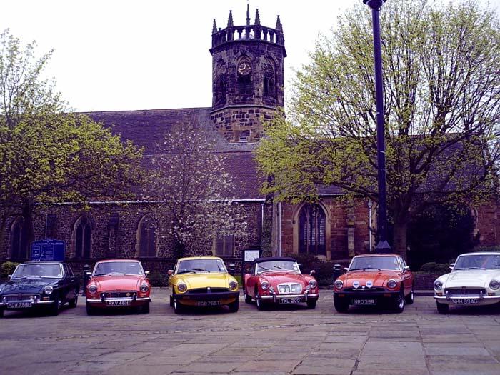 A group of MG enthusiasts assemble on St Georges day in Atherstone market square for a photo shoot.Unfortunately two chavs turned up in rubber bumper cars to interupt the furious pollishing of the chrome bumper brigade!